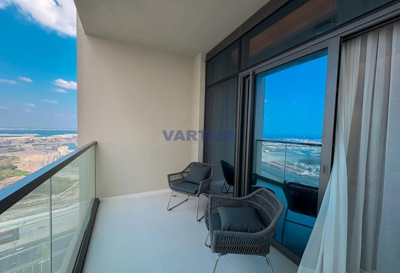 Photo of the balcony with two chairs, beside the living room's glass wall