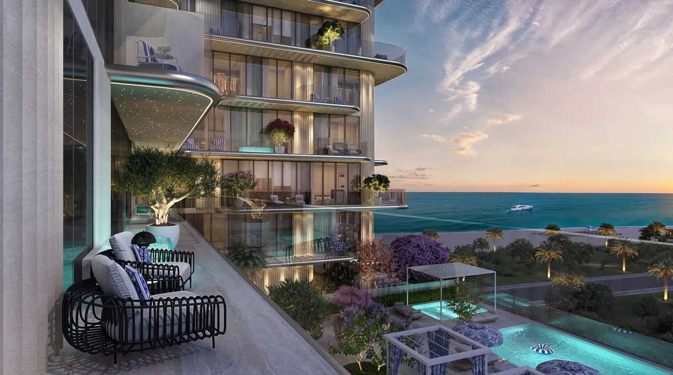 A woven lounger on a balcony at sunset, looking down over the pool deck and out to the sea