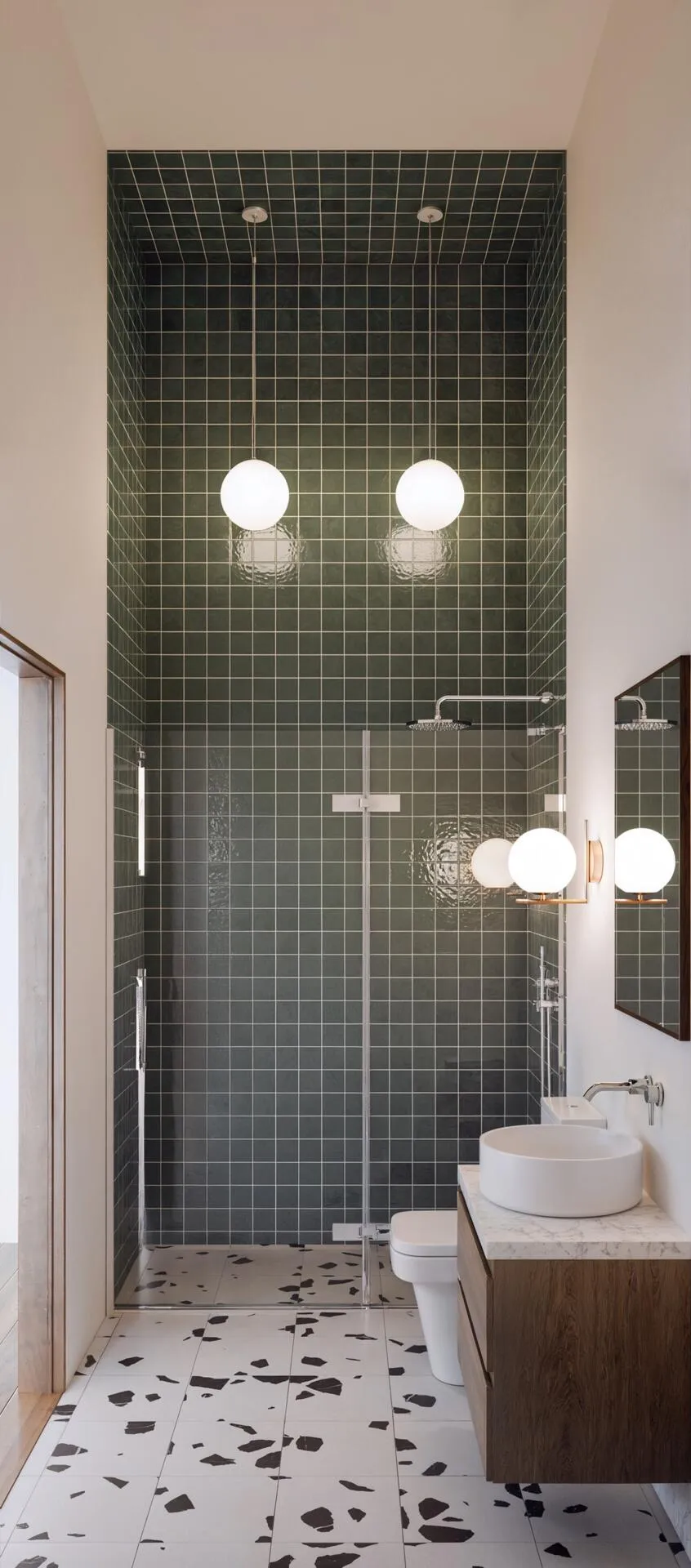 A finished bathroom with green mosaic tiling, a walk-in shower and terrazzo flooring.