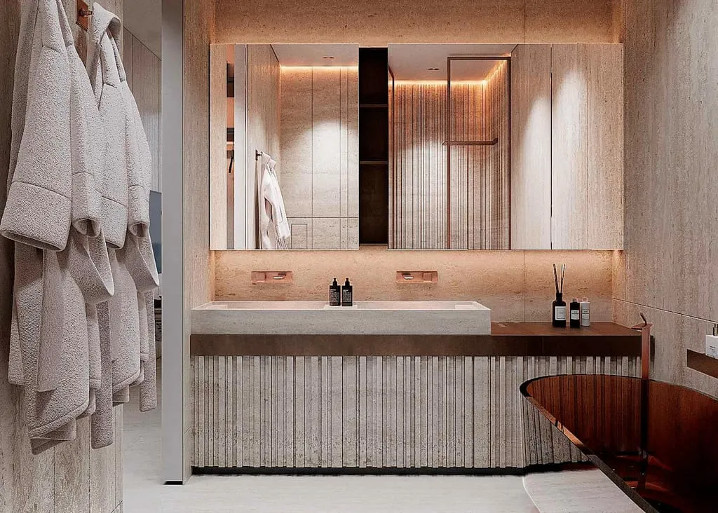 A bathroom vanity under a backlit mirror, robes hanging beside it and a tub at the far end
