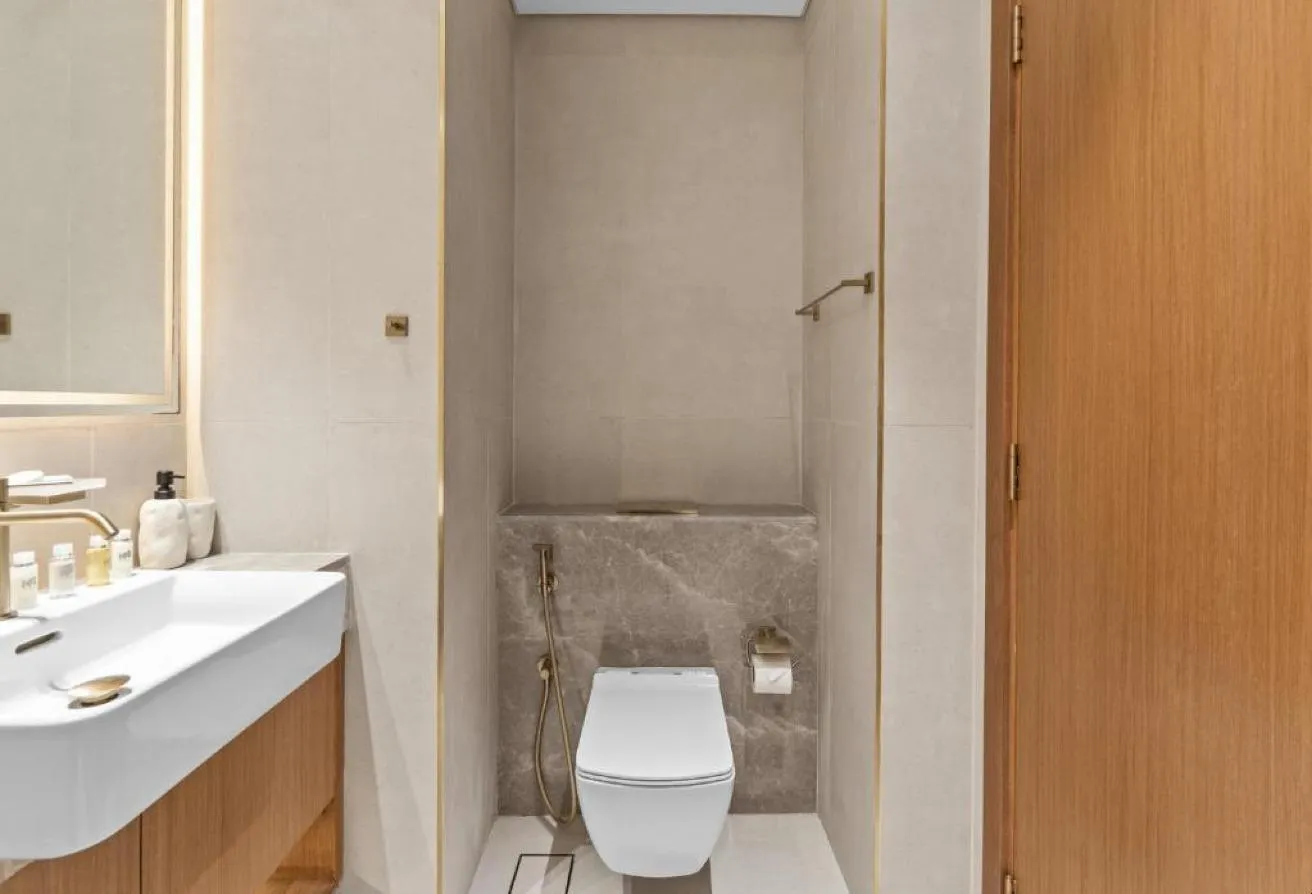 Photo of the bathroom, with a white basin and a toilet in a stone-clad niche