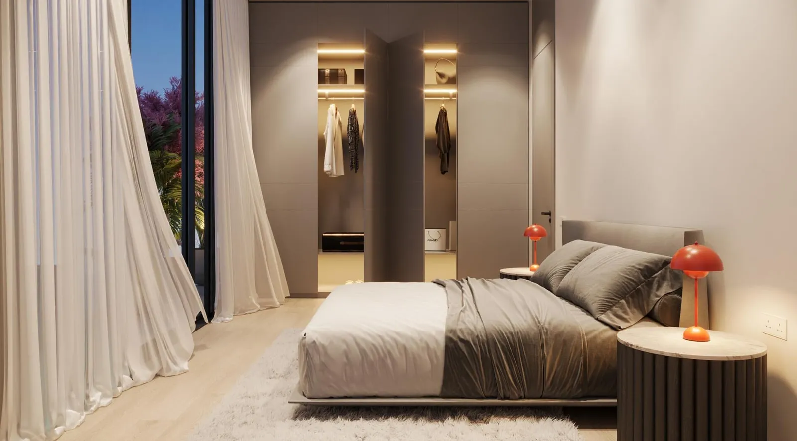 A bedroom with sheer curtains drawn back from the window and a low bedside table