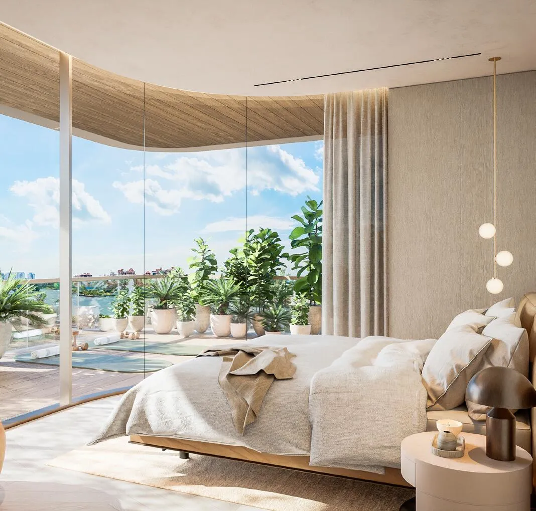 A bedroom with a curved floor-to-ceiling window looking out over the water, plants beside the bed