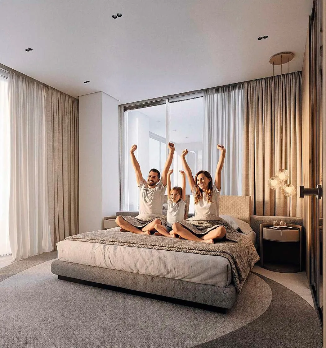 A bedroom with a family sitting on the bed, floor length curtains drawn back from the window