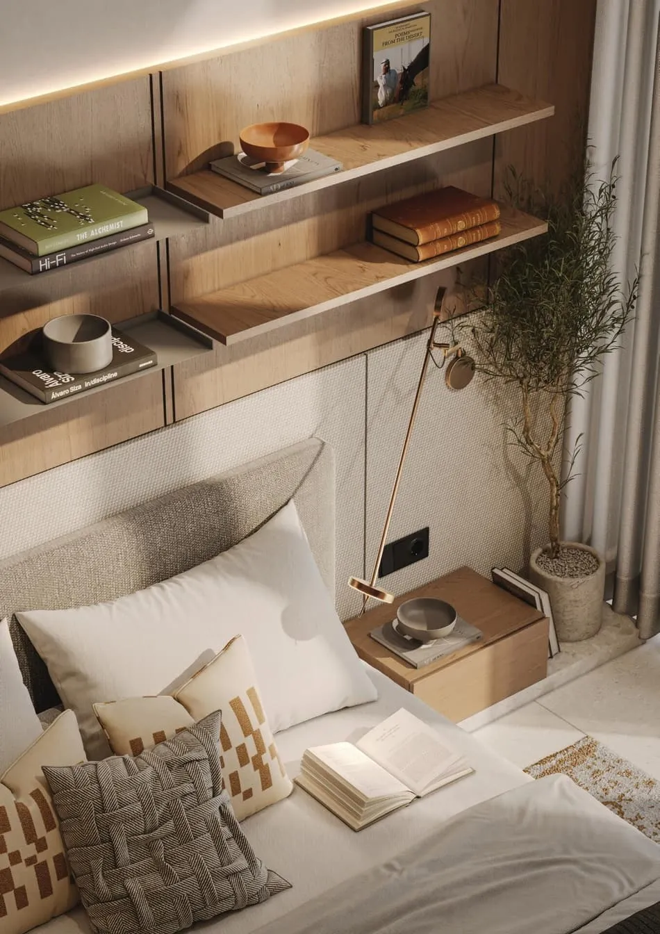 A bedside table under two timber shelves of books, a brass reading lamp angled over the bed