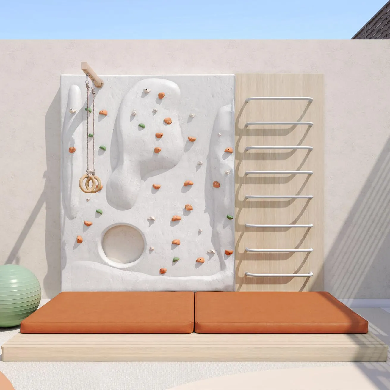 An indoor climbing wall with coloured handholds above orange crash mats