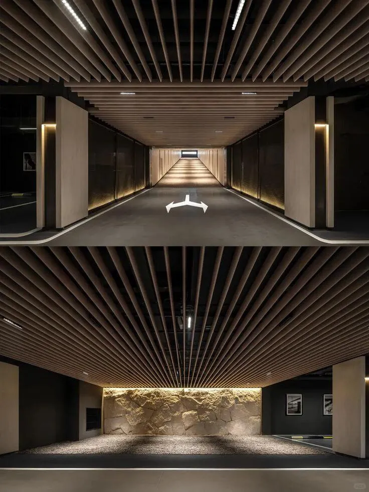 A corridor lined in timber slats, one linear light running the length of the ceiling toward a lit end wall