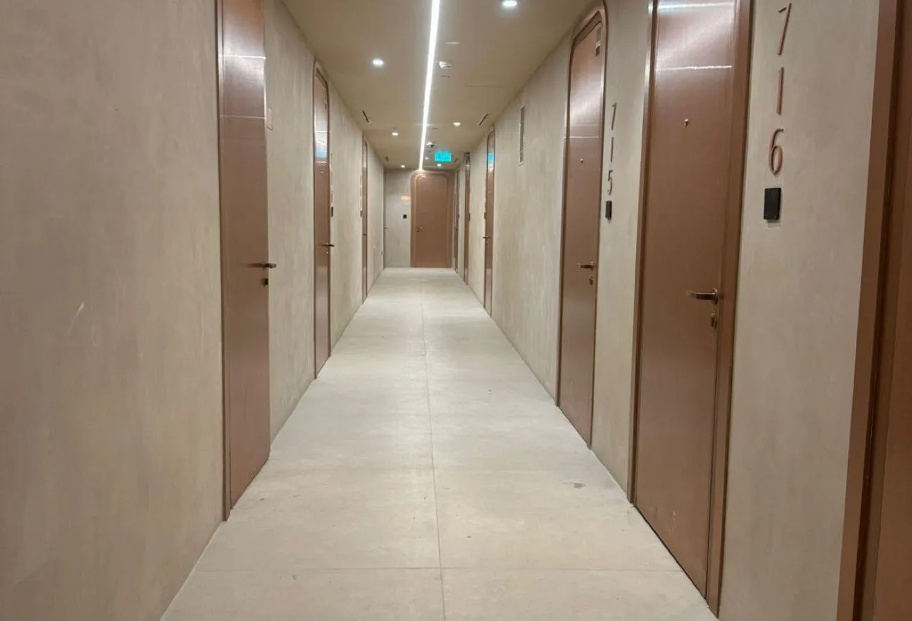 Photo of a residential corridor with pale plaster walls and bronze-framed doors