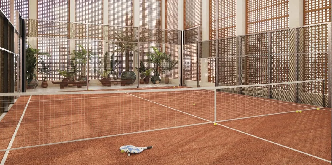 A clay-coloured court behind mesh fencing, a net across the middle and a ball resting on the surface