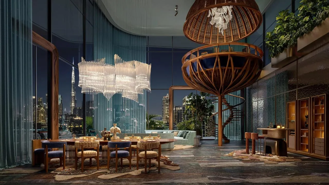 A double height room after dark, woven pendants hanging over the dining table and the city lit behind the glass