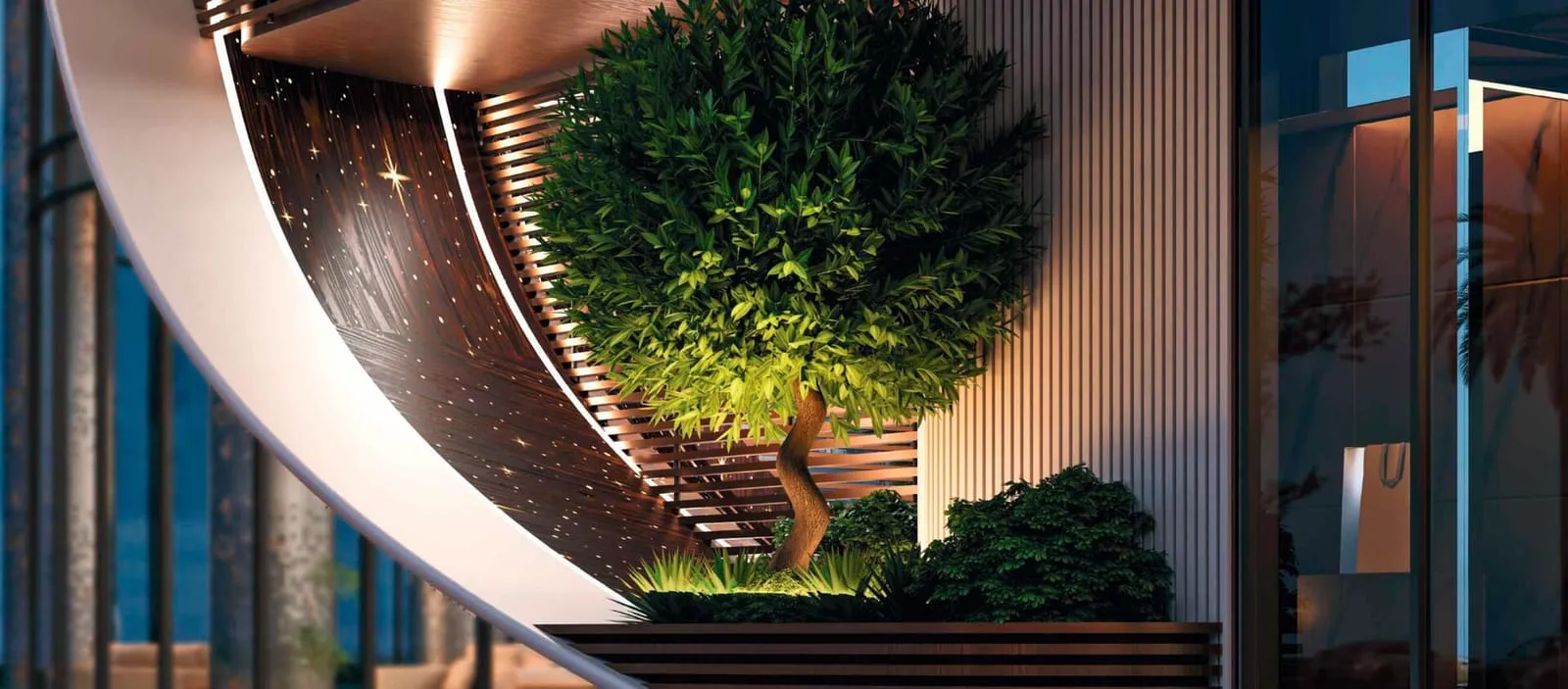 The entrance canopy after dark, a single tree lit beneath the curve of the bronze ribbon