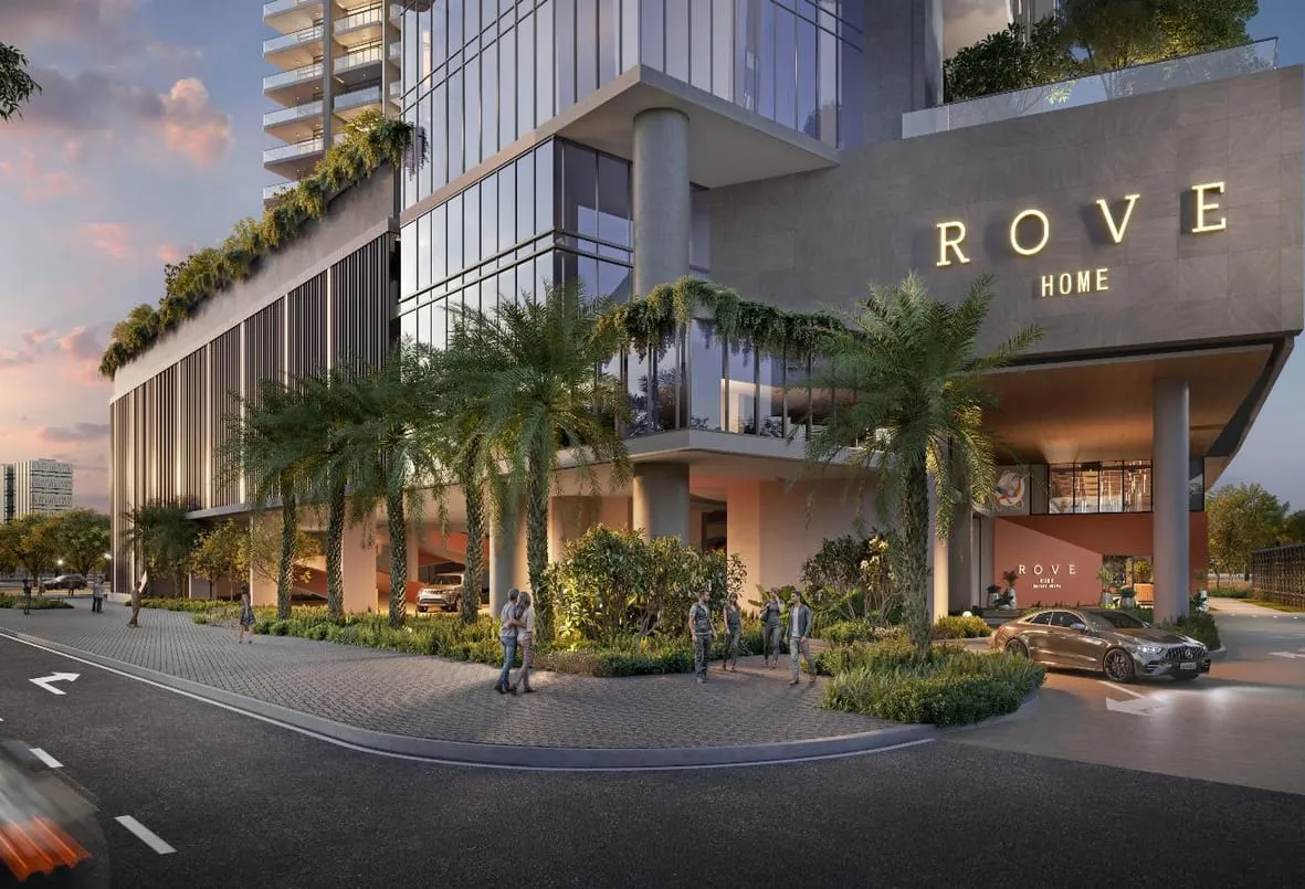 Render of Rove Home Marasi Drive from the street at dusk, the Rove Home sign above a palm-lined entrance