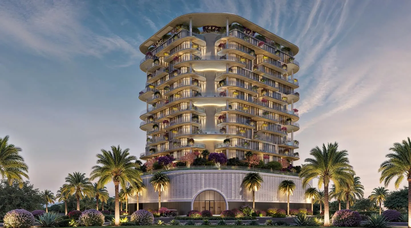 Villa del Brunello seen head-on at sunset, its planted terraces stacked above a lit arcade and a row of palm trees, with the beach to one side