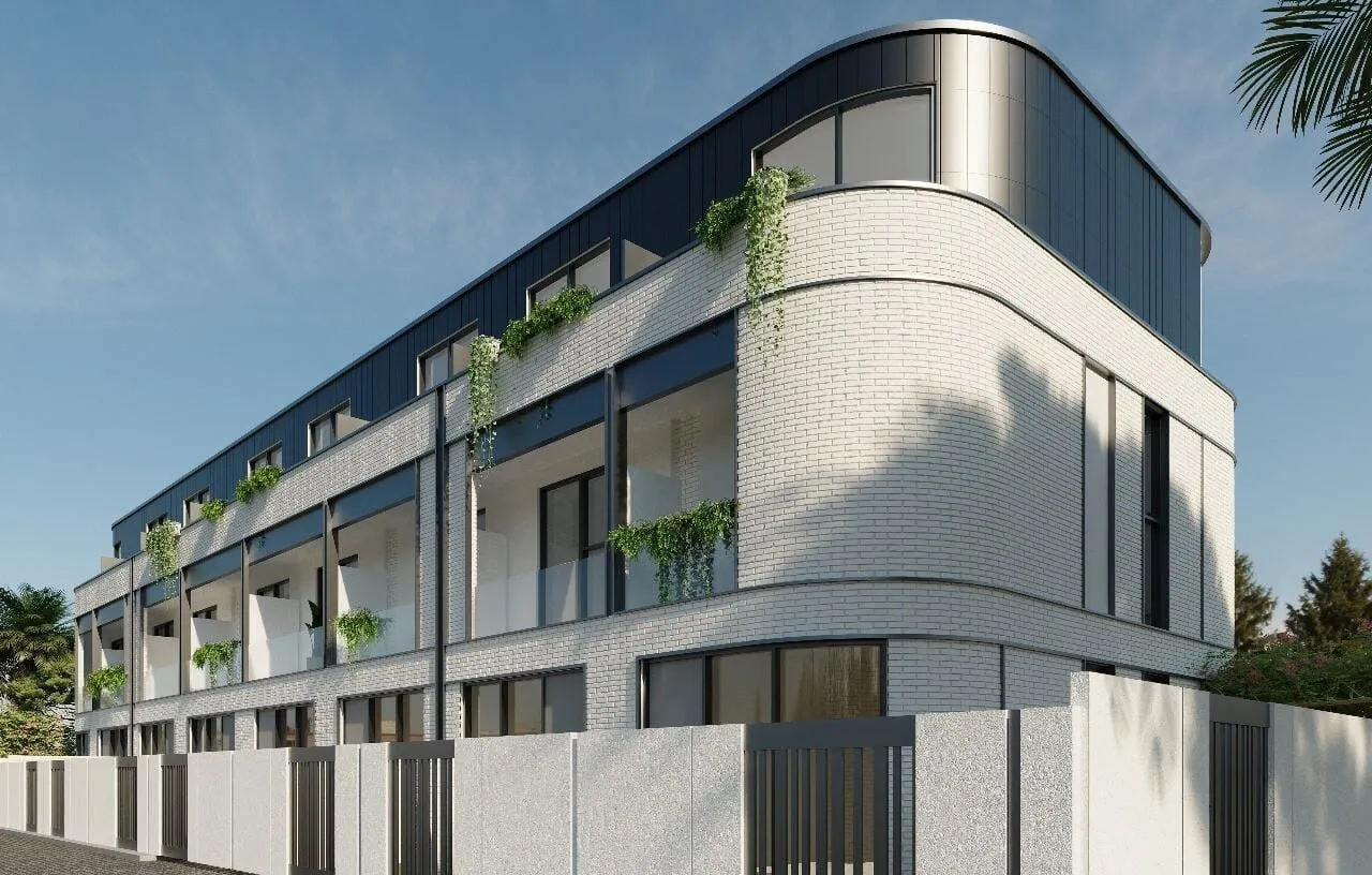 The curved white brick corner of a Taormina Village townhouse block, planted terraces above the ground floor