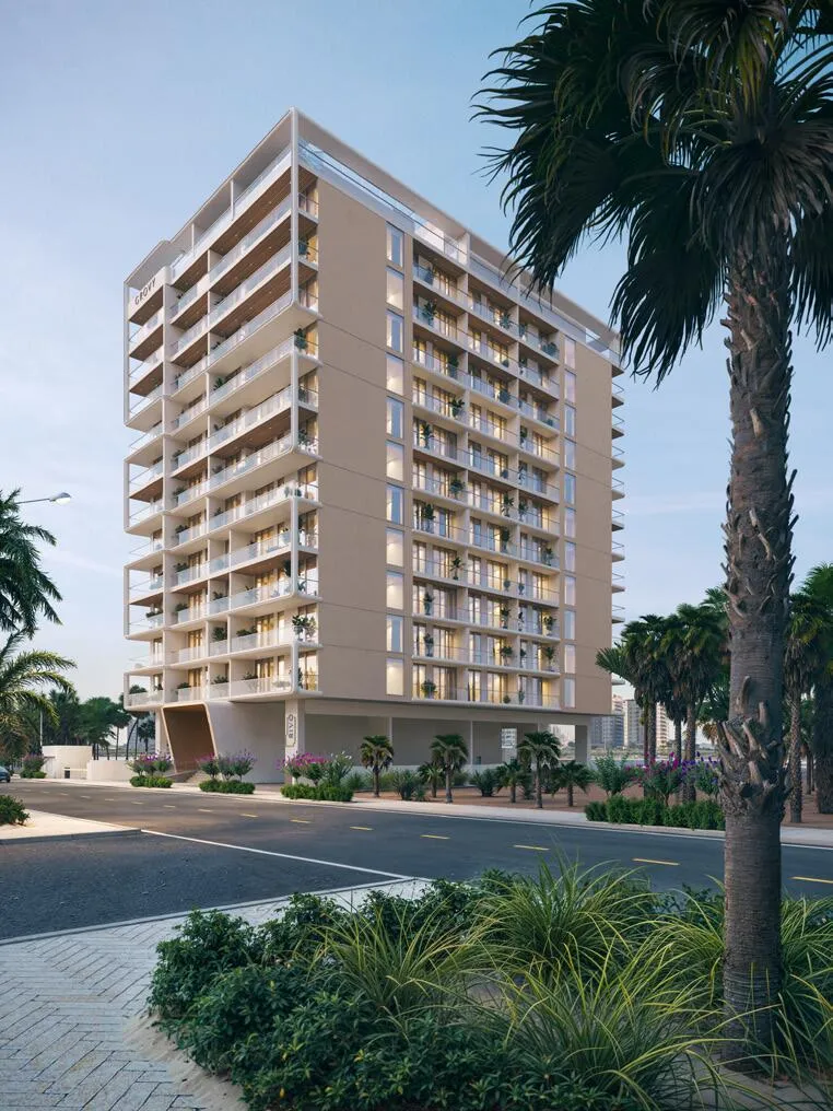 A close street-level view of the tower's corner, the developer's name set on the crown above a palm tree