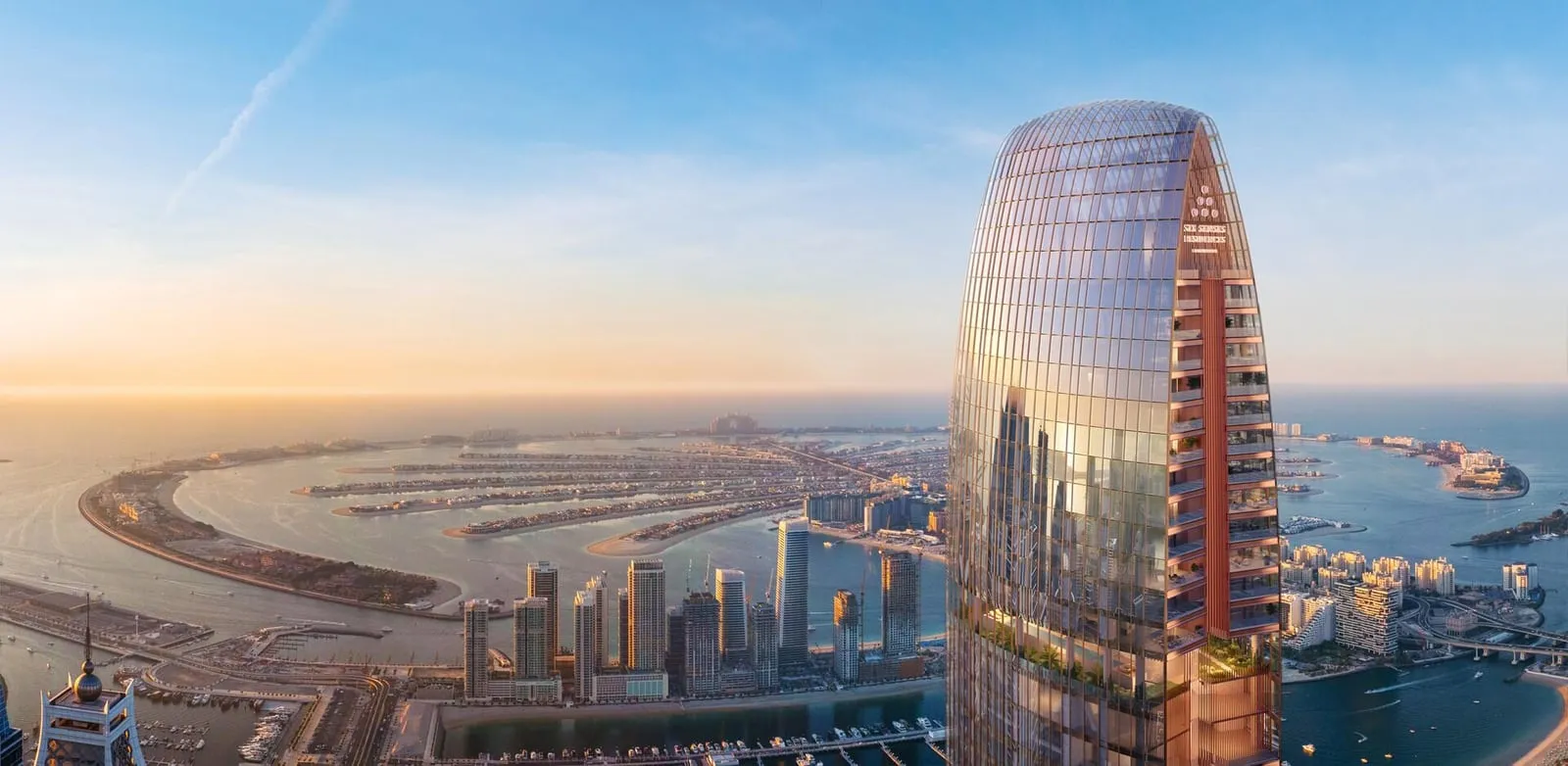 The tower's oval crown seen from above at sunset, Palm Jumeirah and the marina spread out behind it
