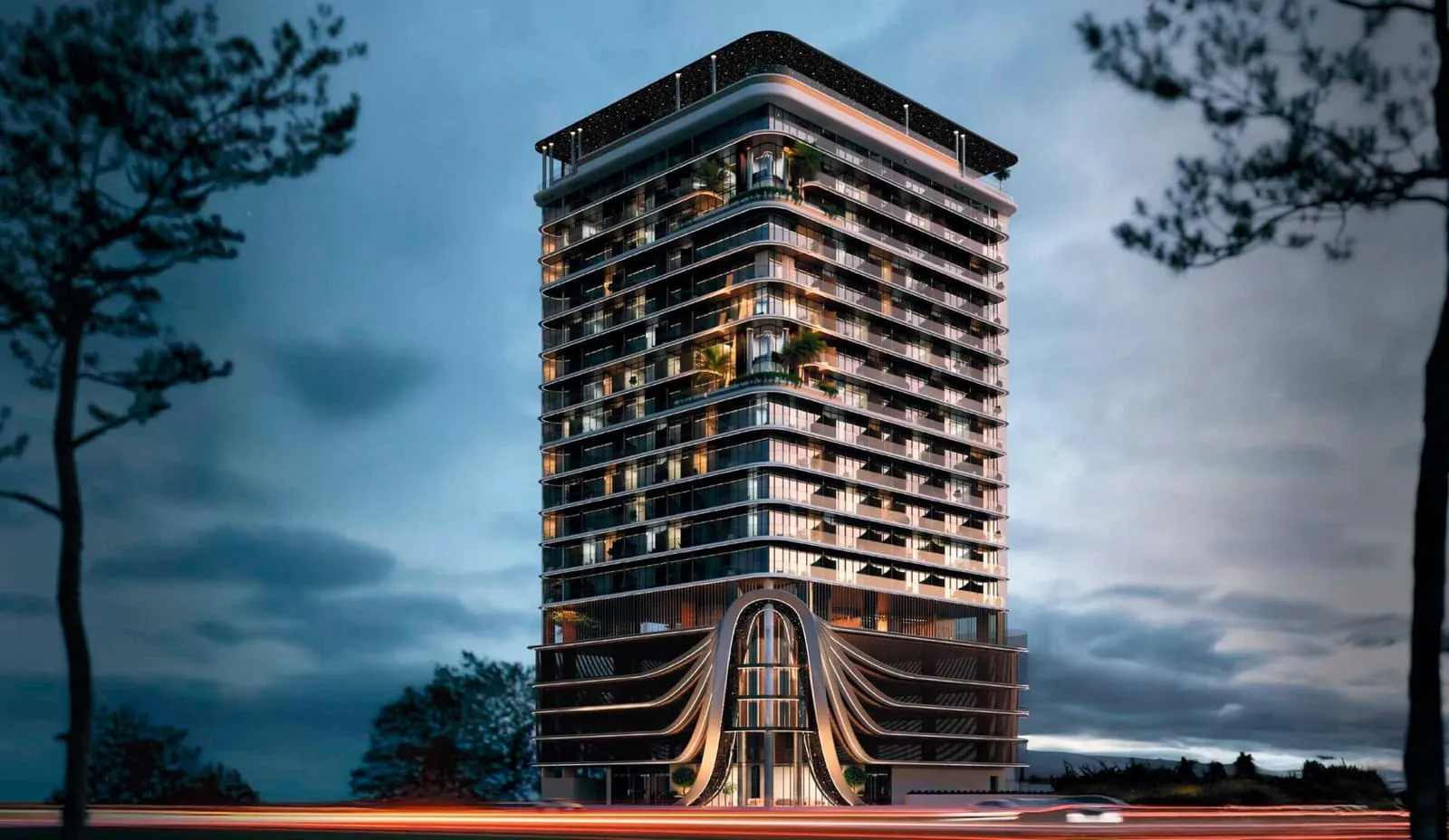 The tower at dusk between two pines, its balcony bands and curved base lit warm against a grey sky