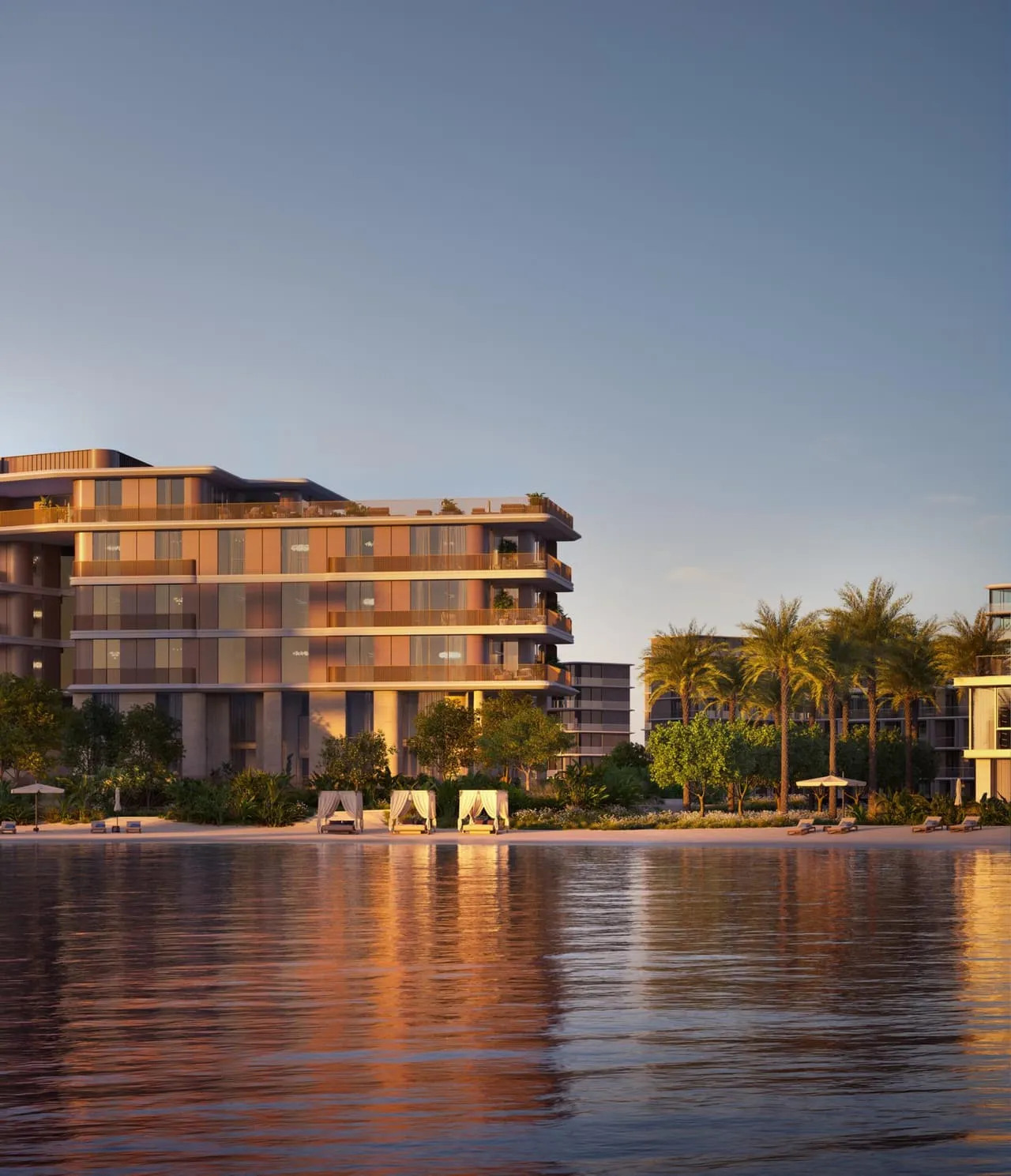 The building at dusk from across the water, its lit facade reflected the full width of the channel