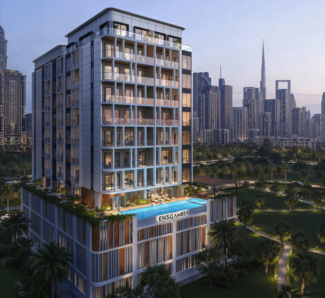 Amber by Enso at dusk, its balcony grid lit above a podium pool, the Downtown skyline behind