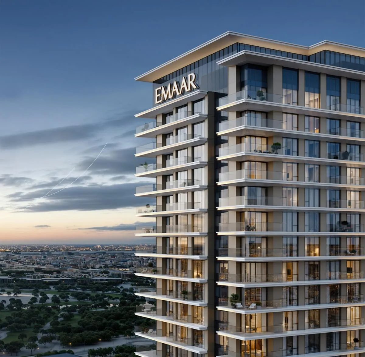 The tower at dusk, balconies stepped along its full height under an EMAAR roof sign, lit windows above the treeline