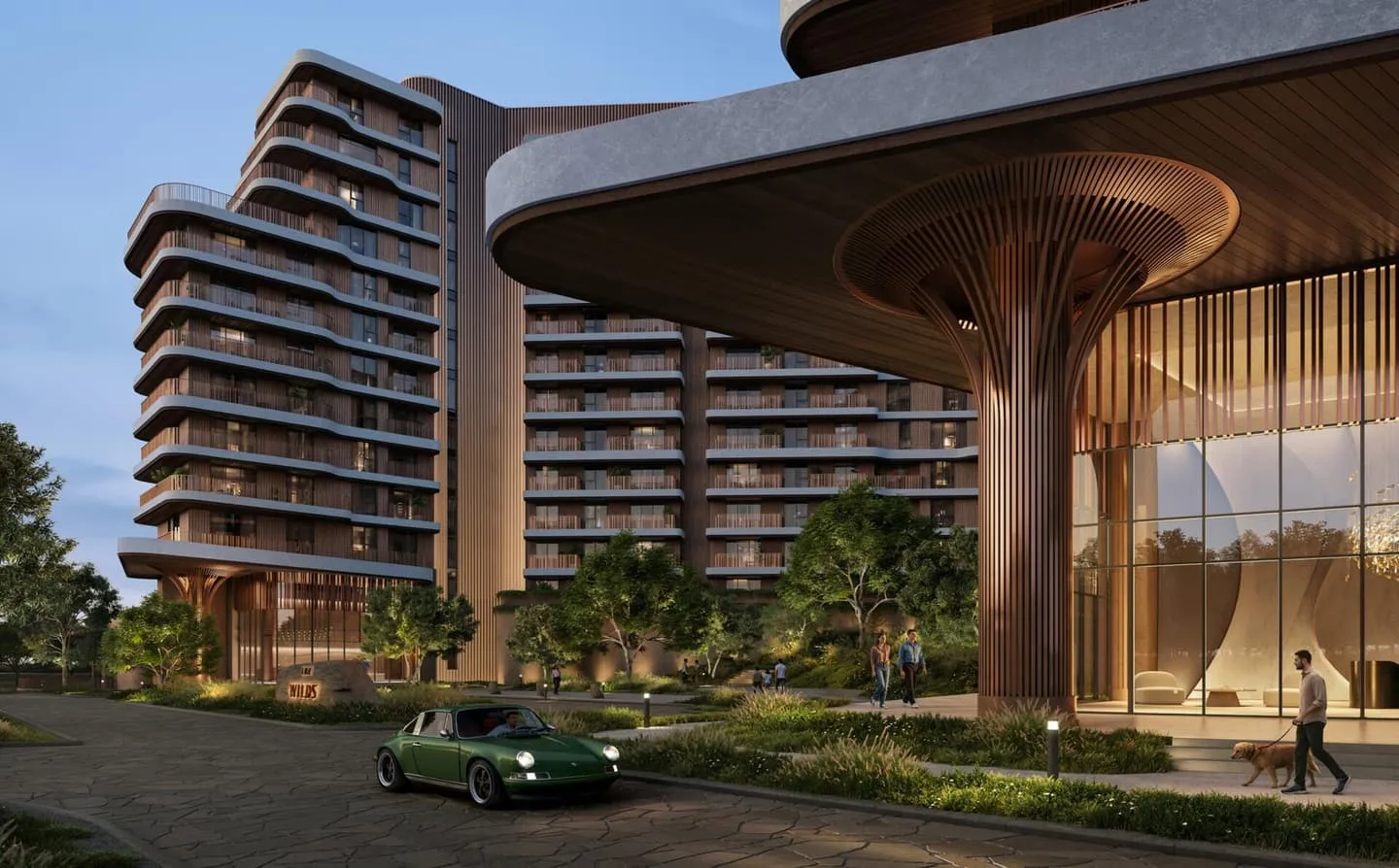 The Wilds Residences at dusk, curved balcony bands above a flared timber column carrying the lobby canopy, a green sports car parked on the paving