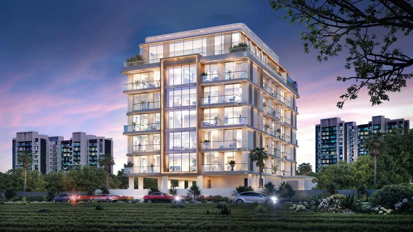 The building at dusk, its balcony bands lit warm against a deep blue sky above the treeline