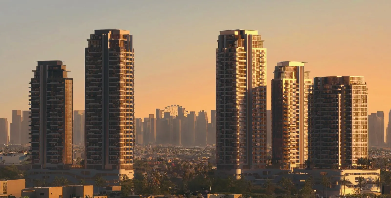 The towers at golden hour, warm light running down the balcony stacks with the wider skyline behind