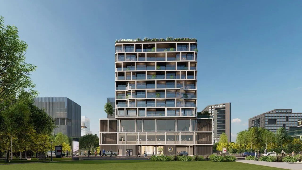 The Grandala seen from the park, planted balconies stacked above a glazed podium