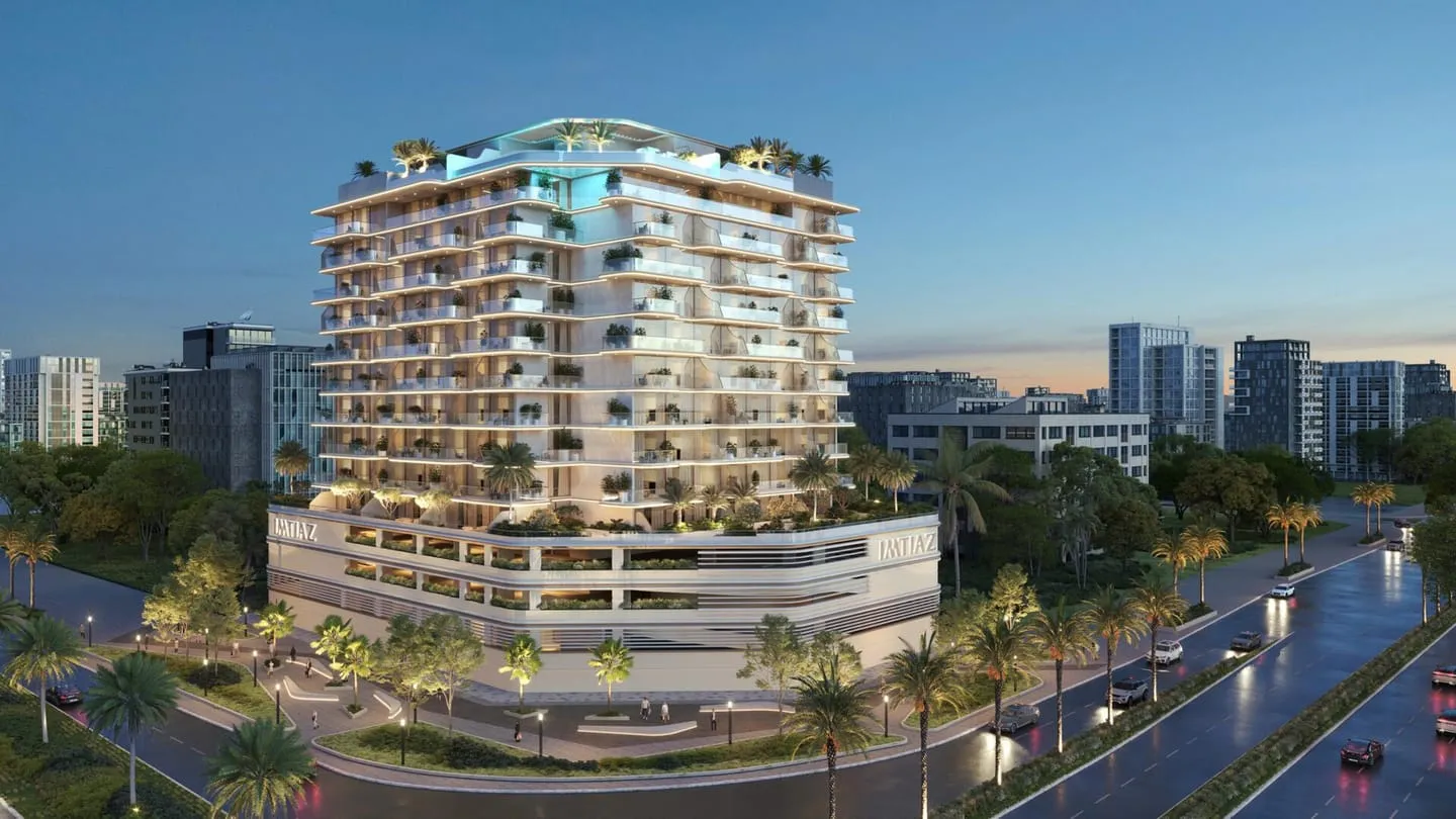 The building from the street in daylight, curved balconies running its full length above a row of young palms