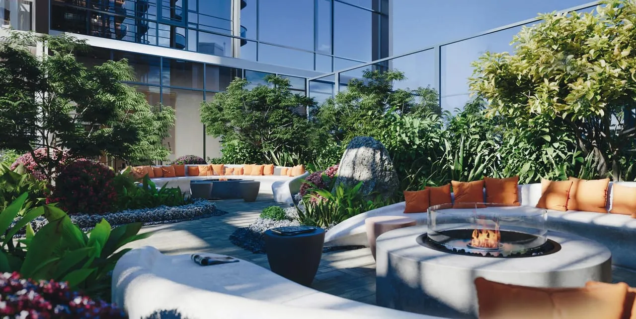 A circular firepit seating ring in daylight, dense planting on one side and the tower rising on the other