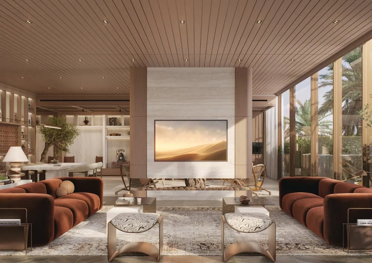 A lounge with a screen set into a stone chimney breast and two rust-coloured sofas facing each other