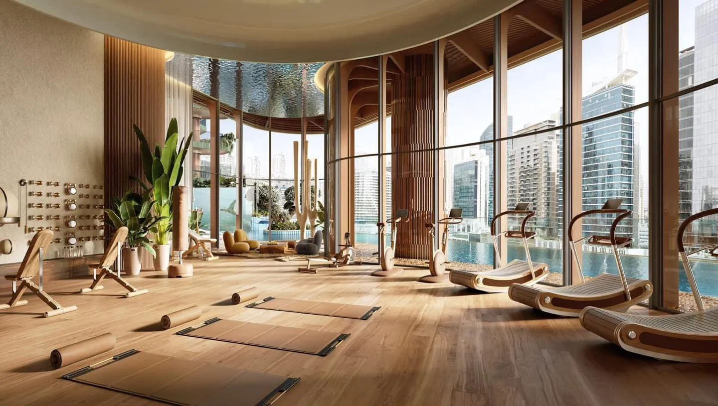 A fitness room, timber equipment set along the windows on a wooden floor with planting between