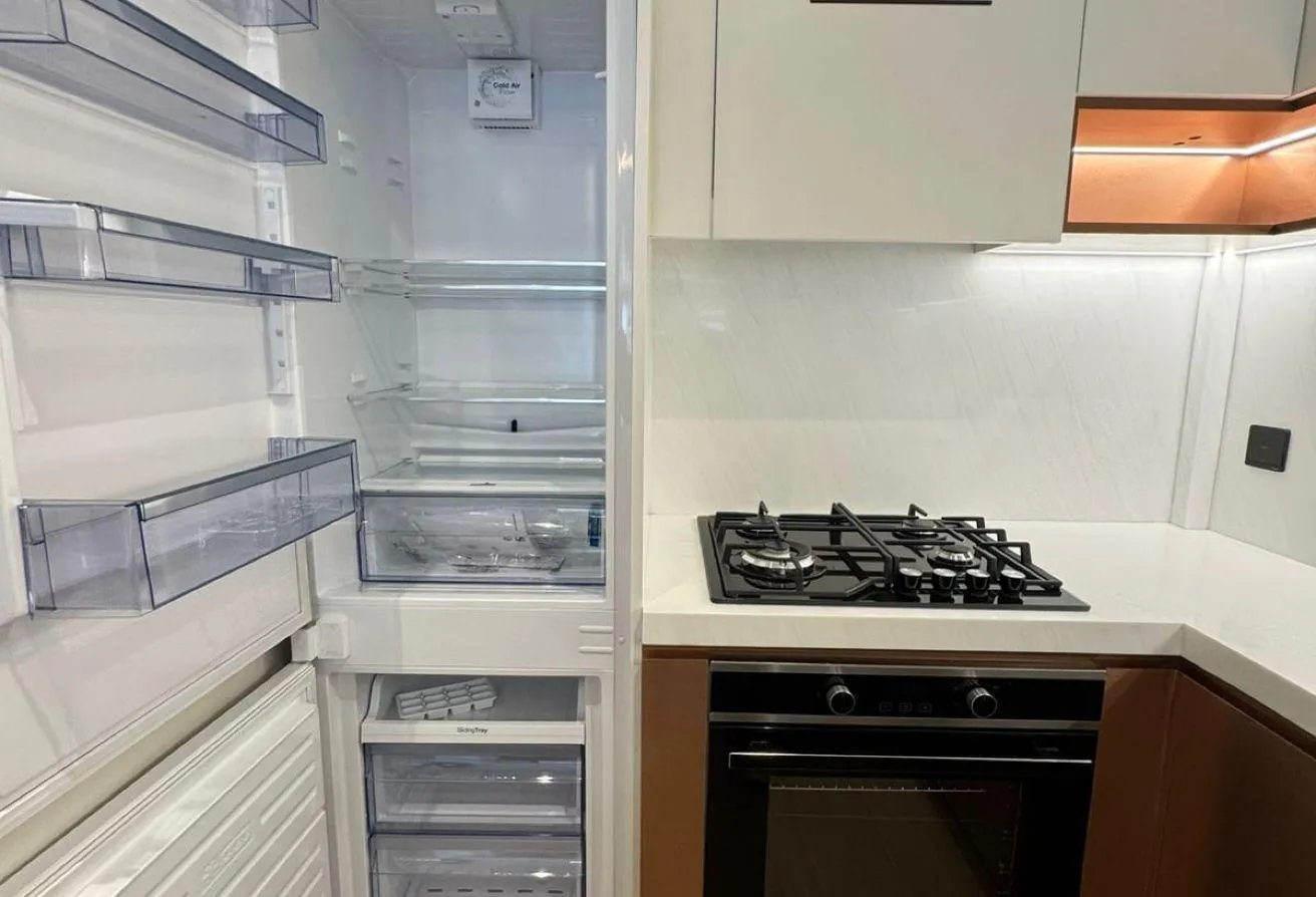 Photo of the open fridge beside the hob and oven