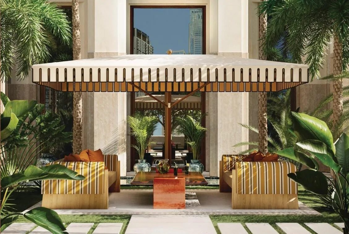 A garden pavilion under a fluted canopy, armchairs facing each other between beds of tall planting
