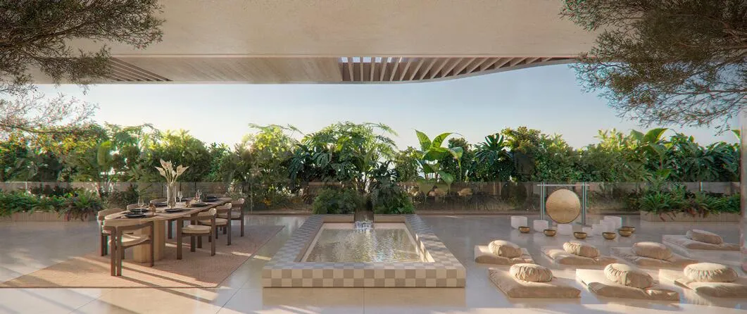 A landscaped garden terrace with a shallow water feature, a dining table and daybeds among the trees