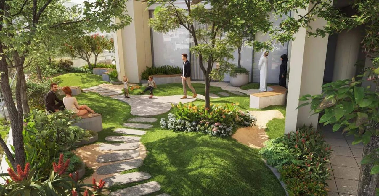 A planted walkway winding between the podium columns, flowering beds and lawn to either side