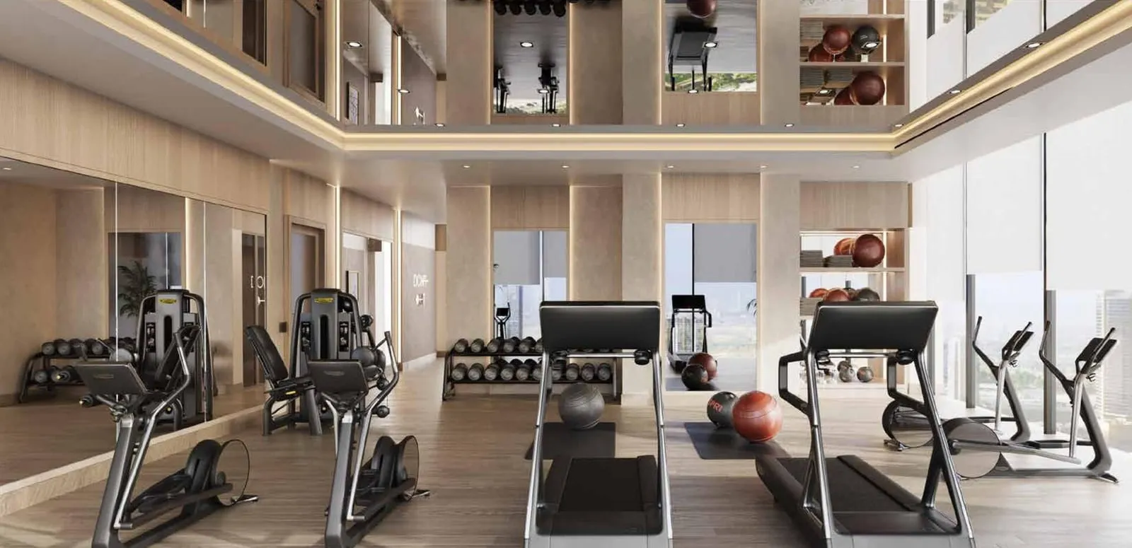 The gym's cardio machines and free weights beneath a double-height glazed wall