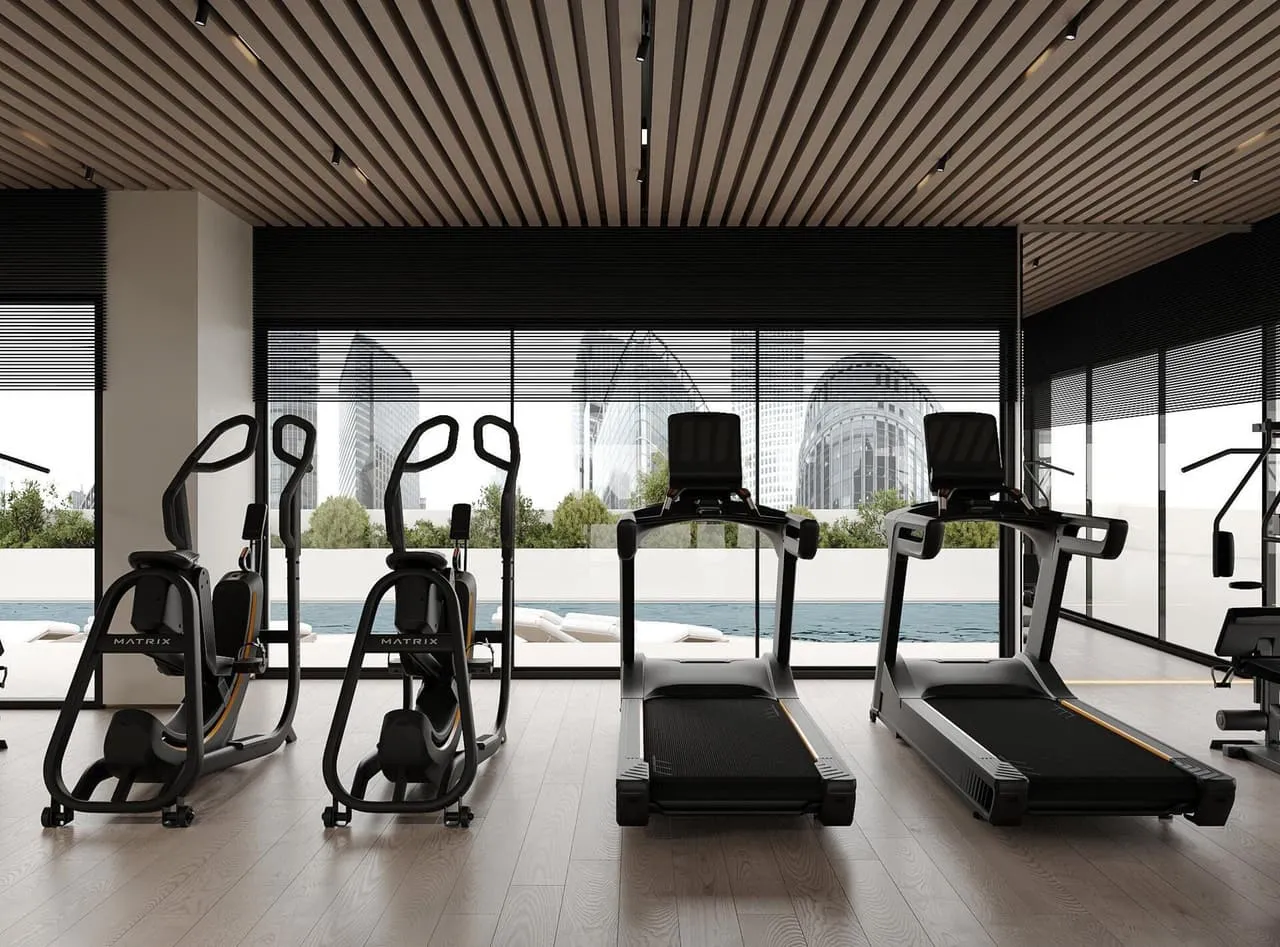 The gym's cardio machines lined along the window wall under a timber-slatted ceiling