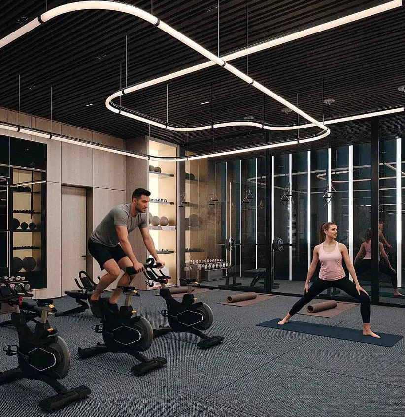 Cycling machines and a mat by the glass wall, two residents training under the same looping light