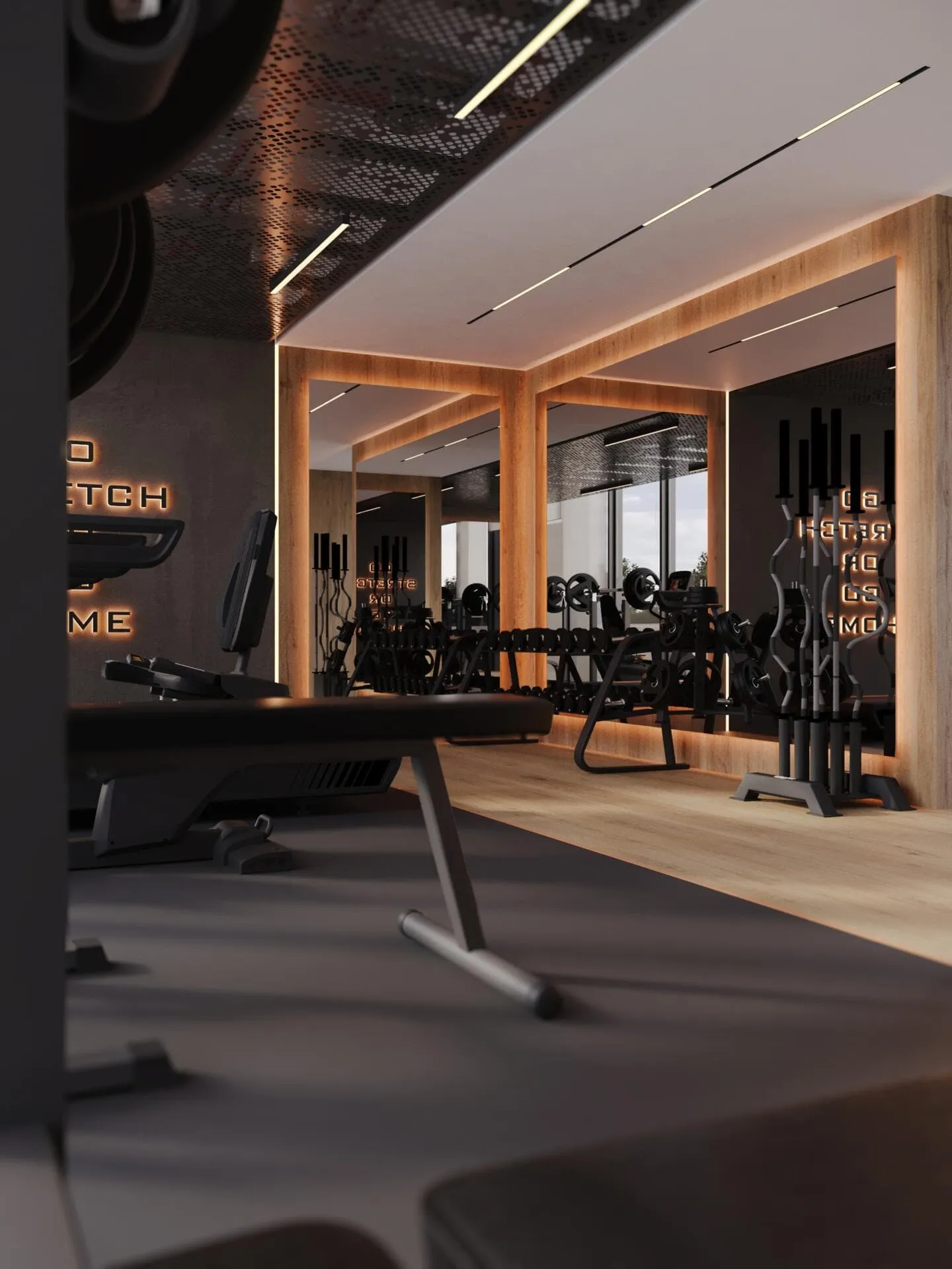 A darker corner of the gym, benches on rubber flooring in front of a mirrored wall lit from behind in orange