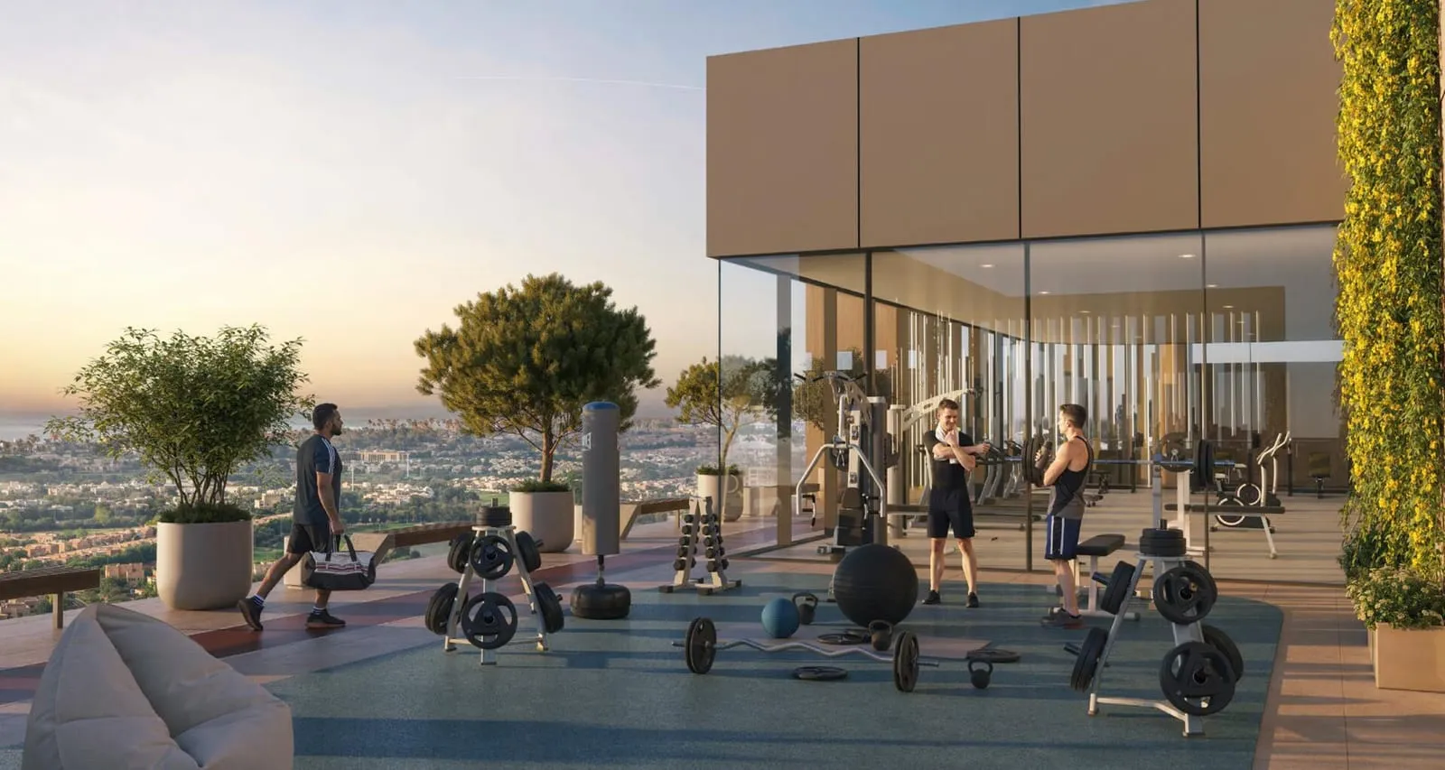 The open-air gym deck at sunset, free weights and benches on blue flooring with the city spread out behind