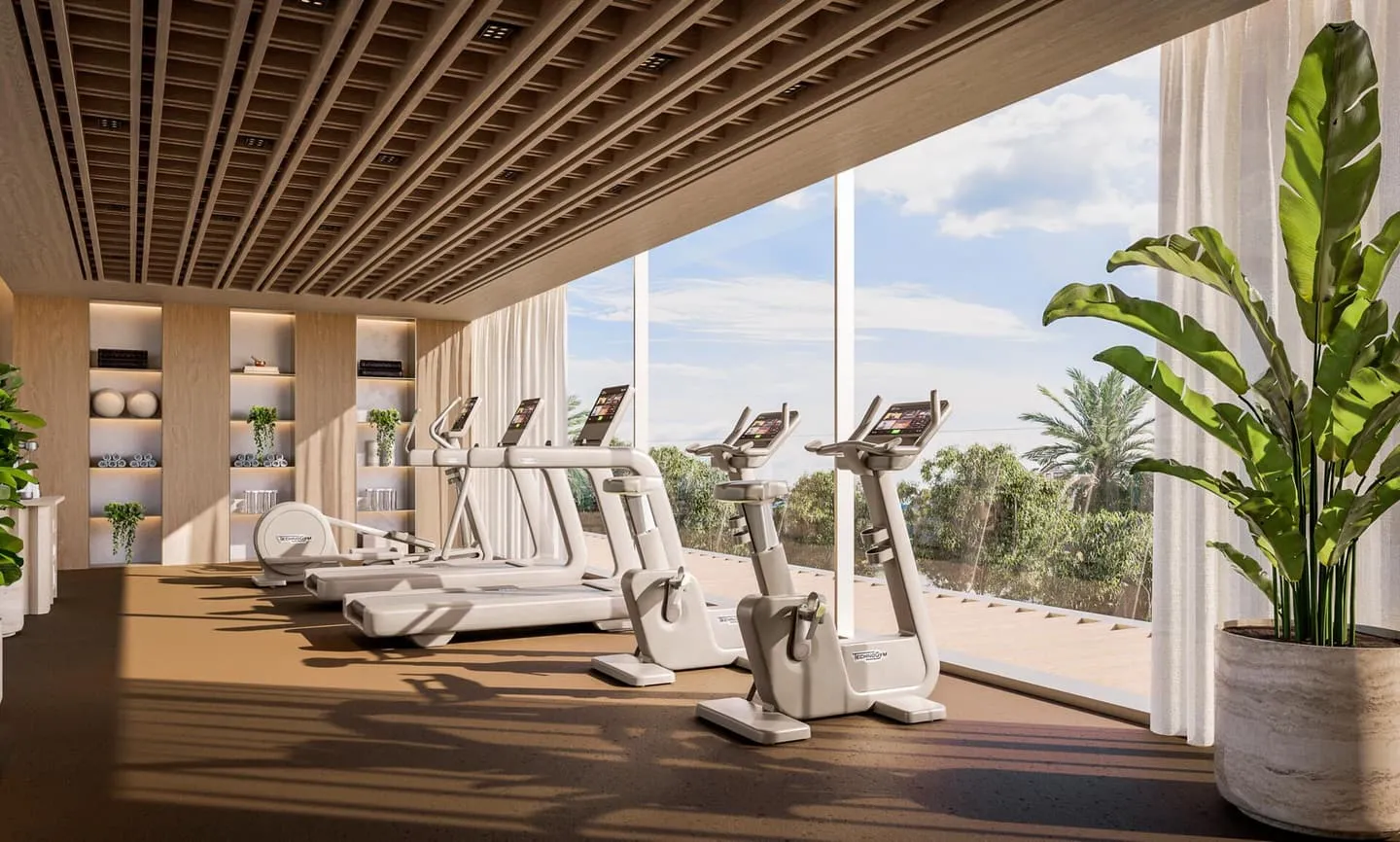 The gym's treadmills lined along a glazed wall, with plants and a view out to the greenery
