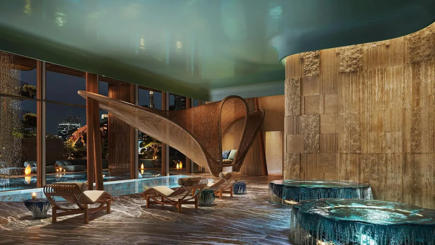 An indoor pool under a curved ceiling, loungers along a ribbed stone wall and a circular jacuzzi at the near end