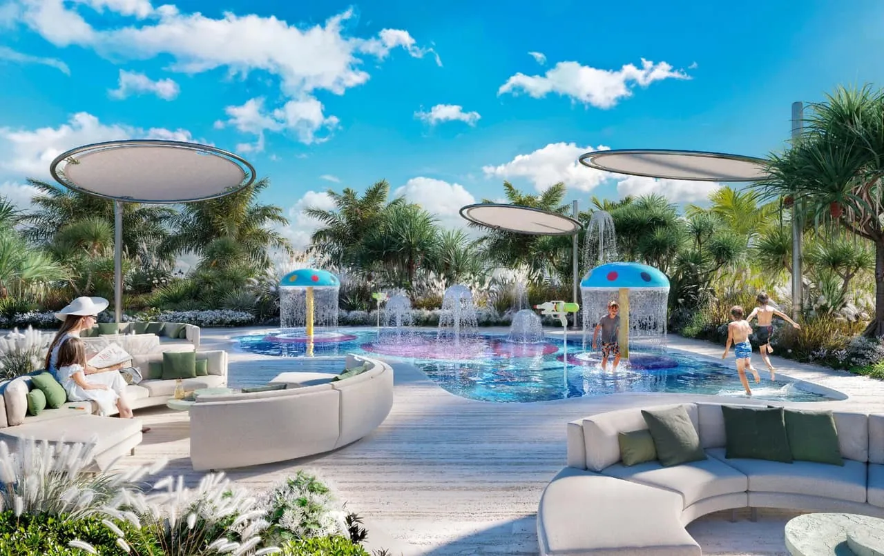 A children's splash pad under shade sails, curved seating around it and planting behind
