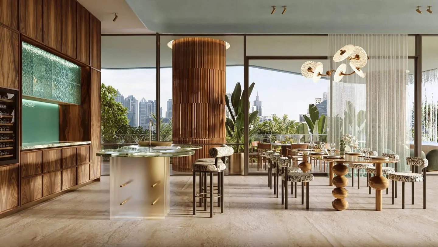A kitchen counter with bar stools beside a round timber column, backlit green glass shelving on the wall behind