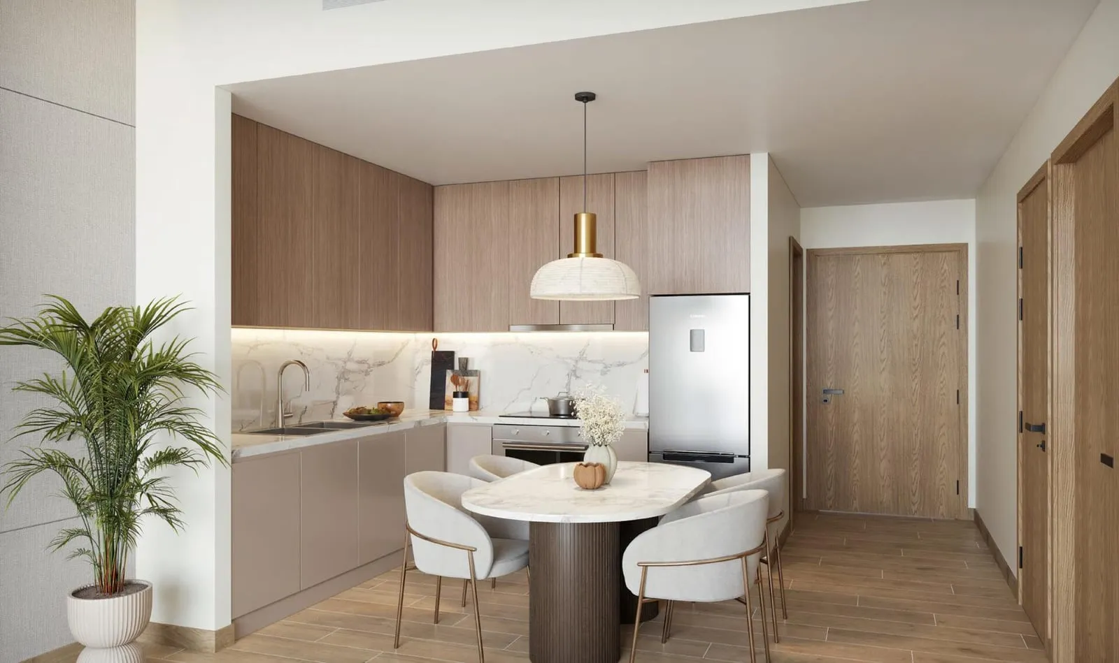 A galley kitchen in pale cabinetry beside a round dining table with upholstered chairs and a potted palm