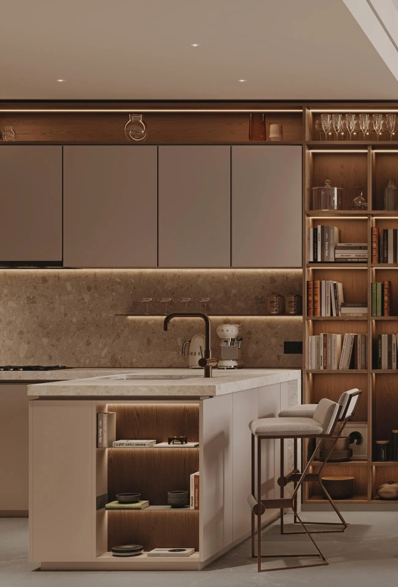 A kitchen island in pale stone with a full-height bookcase running alongside the cabinets