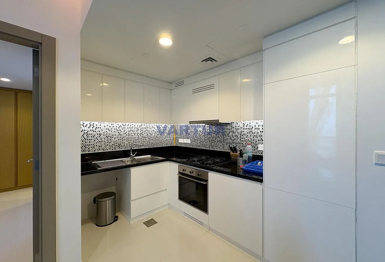 Photo of the kitchen with white gloss cabinets, a built-in oven and a hob