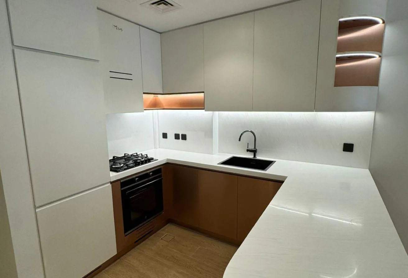Photo of the L-shaped kitchen, with a gas hob, a built-in oven and under-cabinet lighting