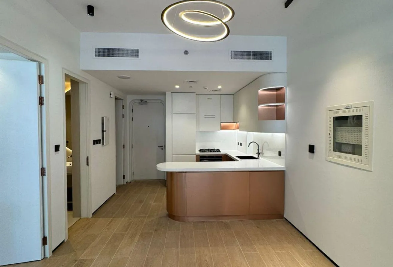 Photo of the living area looking towards the open kitchen, under a ring pendant light